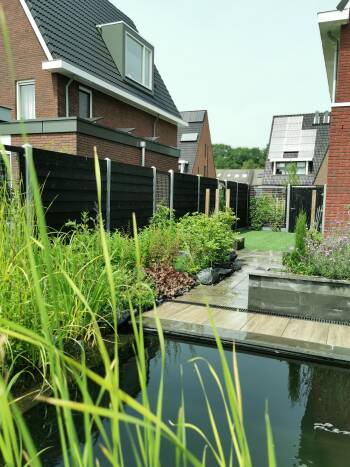 Deze zwarte Zweeds rabat schutting zorgt ervoor dat onze groene (water) planten in en rondom onze natuurlijk zwemvijver, allemaal tot z'n recht komen. Daarnaast hebben we op een speelse en natuurlijke manier meerdere groenstroken gecreëerd tussen de schutting panelen in en naast de schuttingdeur. We genieten elke dag van onze tuin! 