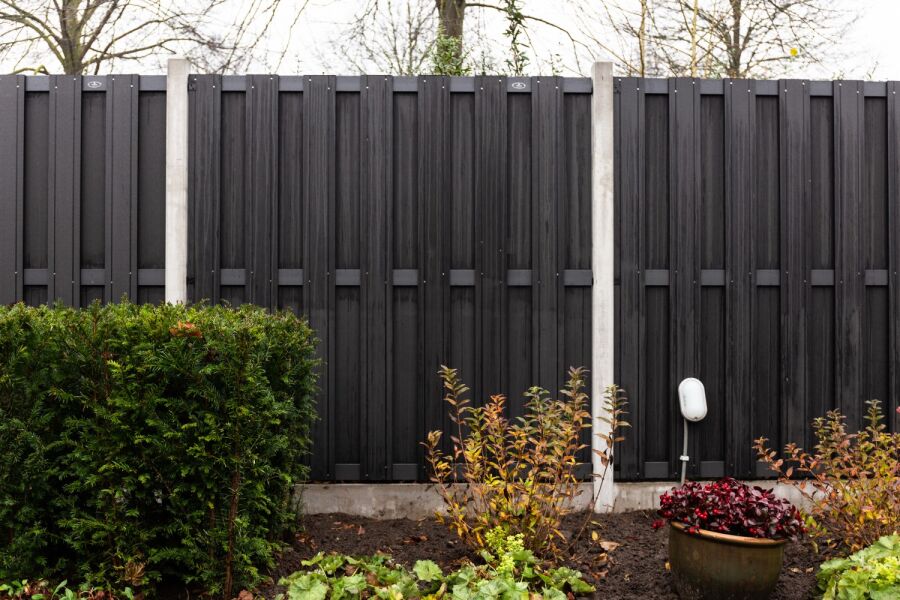 Zwarte composiet tuinschermen met betonpalen.