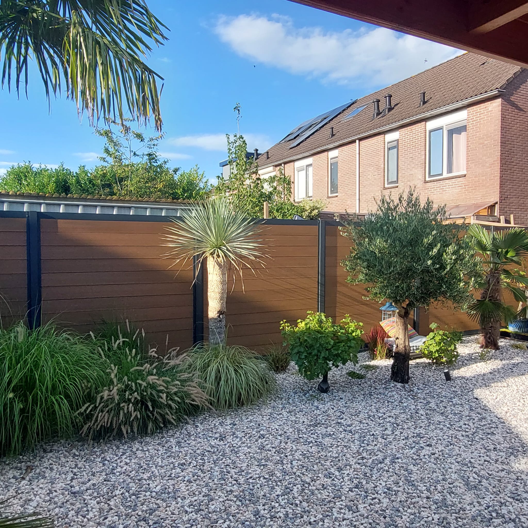 Nadat we enkele jaren geleden een grote veranda hadden geplaatst en de tuin een metamorfose hadden gegeven, waren we nog op zoek naar de ultieme schutting. Deze hebben we gevonden bij Vandentop. Het is een teak composiet schutting geworden met zwarte aluminium palen. Wij zijn erg blij met het resultaat!