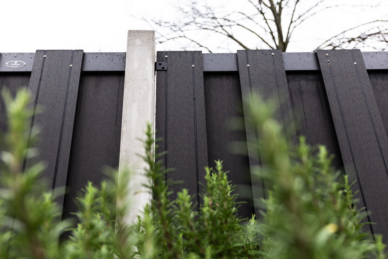 Composiet schutting met grijze betonpalen.