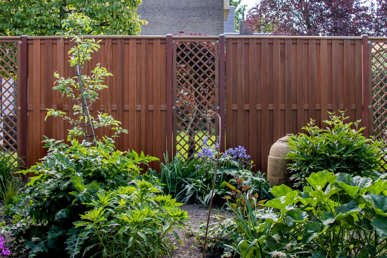 Schutting van hardhouten tuinschermen, hardhouten trellisschermen en hardhouten palen.