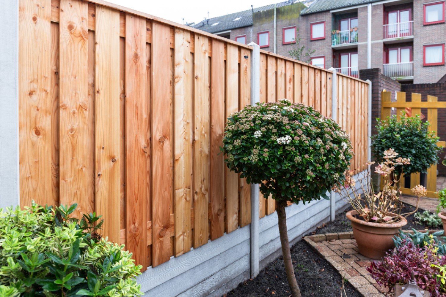 Hout beton schutting douglas tuinscherm met grijze betonpalen en onderplaat met rabatmotief.