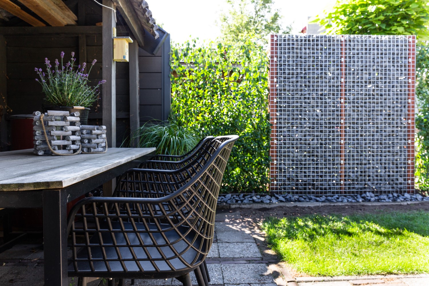 Schanskorf schutting met grijze stenen en hedera schermen.