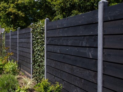Zwart Zweeds rabat schutting met betonpalen en hedera
