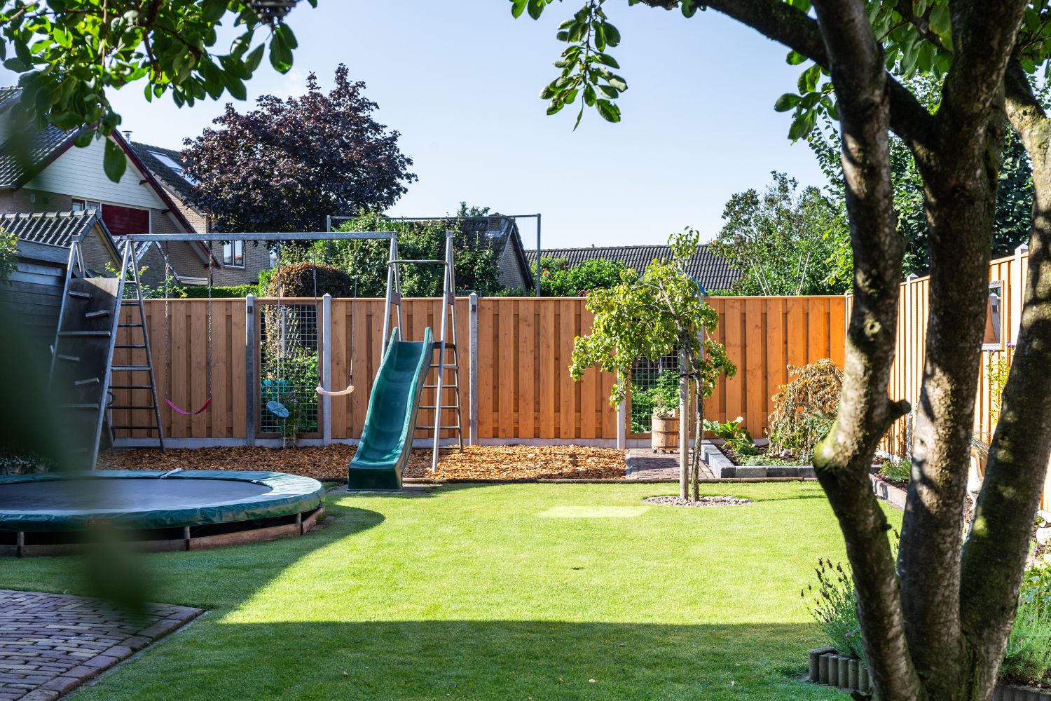 Kindvriendelijke tuin met veilige schutting en speeltoestellen